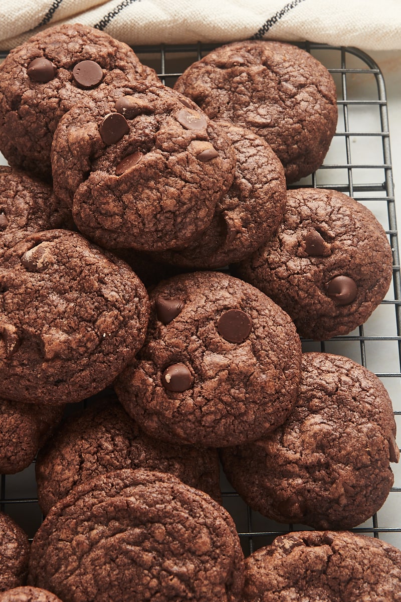 Chocolate chocolate chip cookies piled onto wire rack