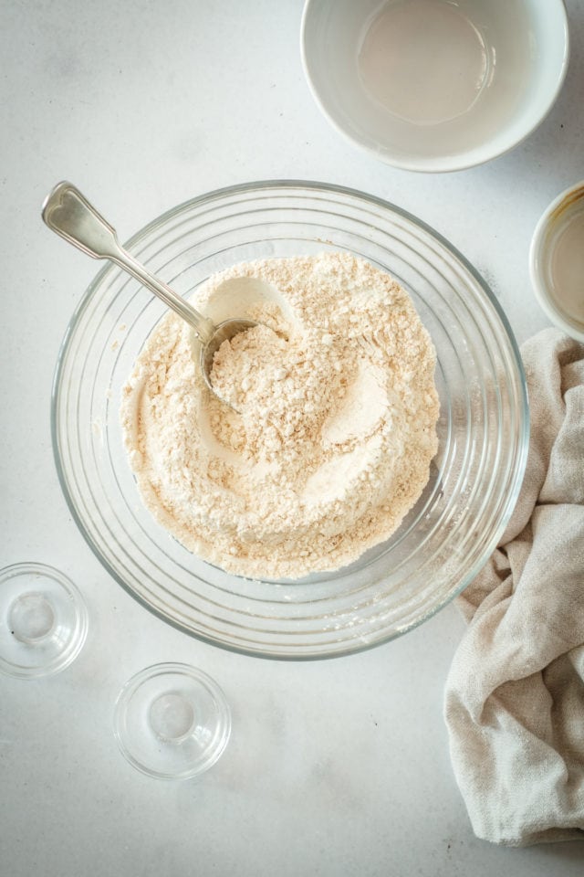 Overhead view of dry ingredients in glass mixing bowl with spoon
