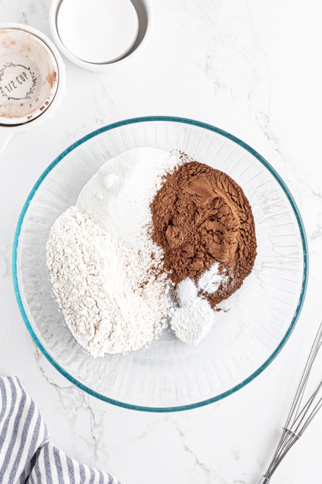 overhead view of flour, sugar, cocoa powder, baking powder, baking soda, and salt in a large glass mixing bowl