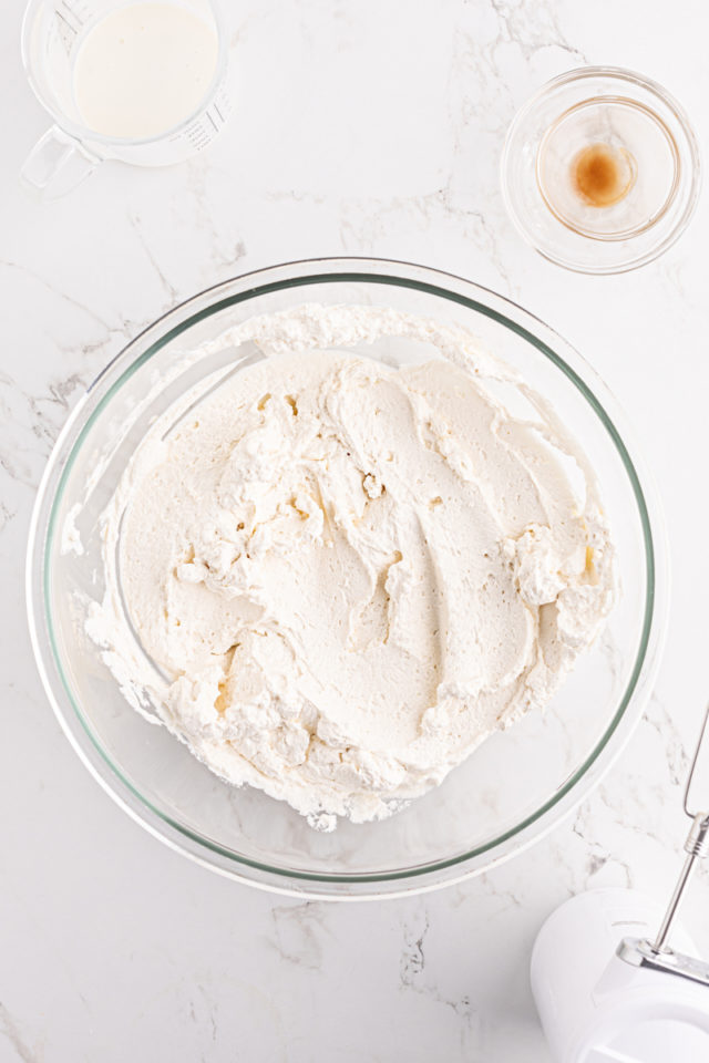 overhead view of freshly whipped cream in a glass mixing bowl